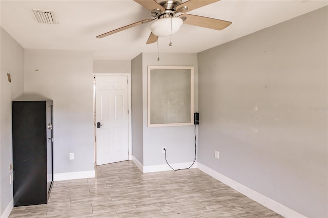 empty room with baseboards, a ceiling fan, and visible vents