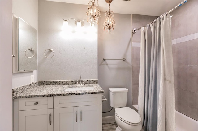bathroom with toilet, a notable chandelier, vanity, and shower / bath combo with shower curtain