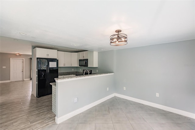 kitchen featuring sink, black appliances, kitchen peninsula, decorative light fixtures, and white cabinets