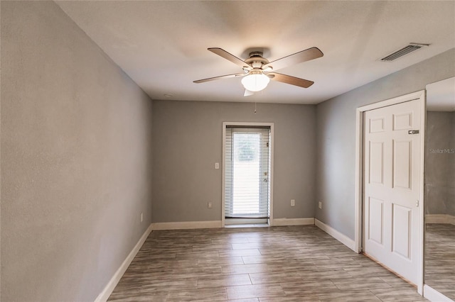 empty room with ceiling fan and light hardwood / wood-style flooring