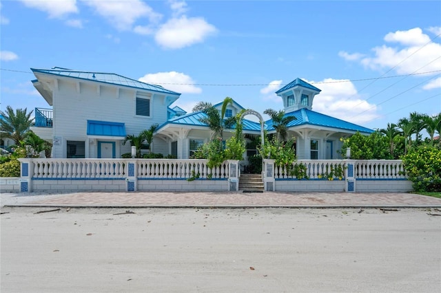 view of front facade with metal roof, a fenced front yard, a porch, and a standing seam roof