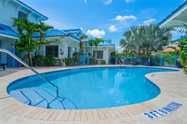 pool with a patio area and fence