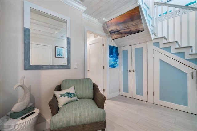sitting room featuring stairway, light wood-style floors, and ornamental molding