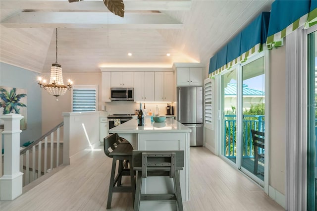 kitchen featuring vaulted ceiling, light countertops, appliances with stainless steel finishes, a kitchen island with sink, and an inviting chandelier