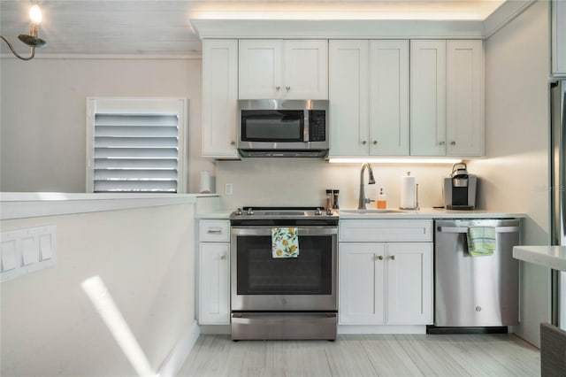 kitchen with light wood-type flooring, white cabinets, appliances with stainless steel finishes, and sink