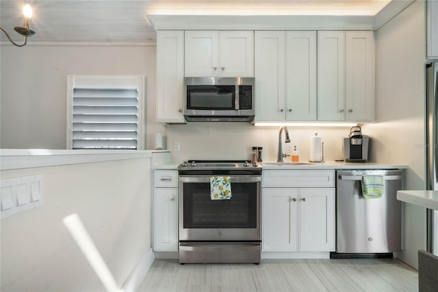 kitchen featuring a sink, light countertops, appliances with stainless steel finishes, and white cabinets