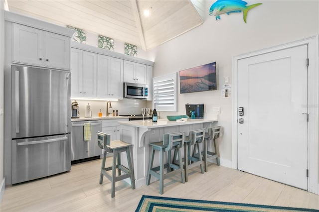 kitchen with light countertops, a sink, a breakfast bar area, a peninsula, and stainless steel appliances