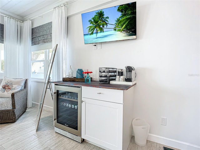 bar with light hardwood / wood-style flooring, wine cooler, wood counters, and white cabinets