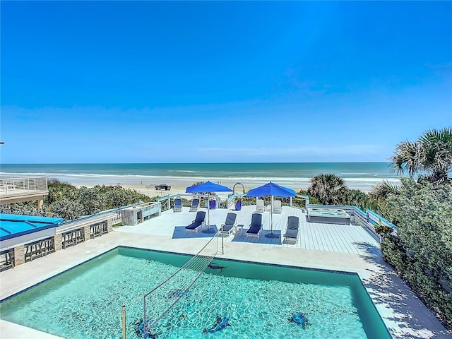 view of pool featuring a beach view, a patio, and a water view