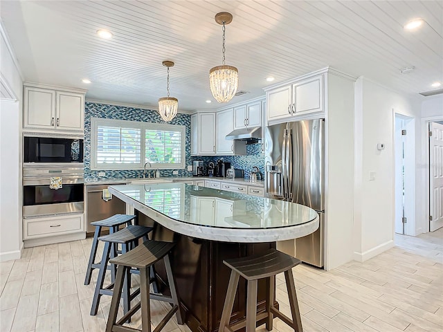 kitchen with backsplash, stainless steel appliances, a breakfast bar area, and under cabinet range hood