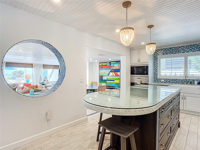 kitchen featuring an inviting chandelier, wood finish floors, baseboards, backsplash, and built in microwave