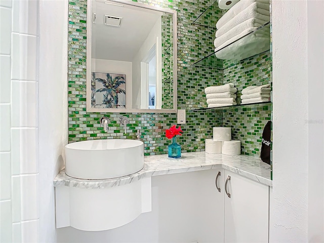 bathroom featuring visible vents, decorative backsplash, and vanity