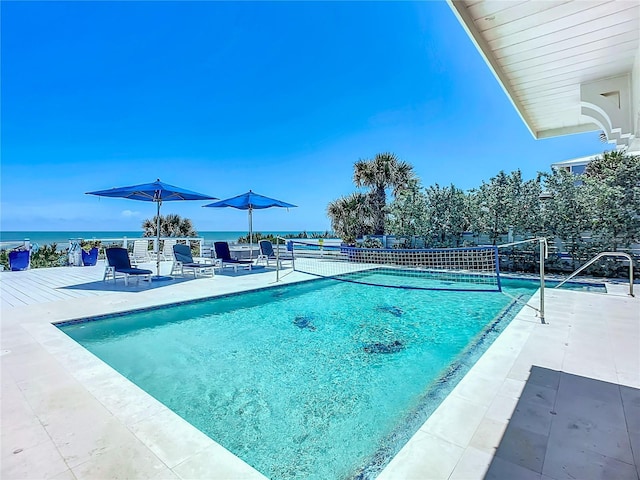 view of swimming pool with a water view, fence, and a patio