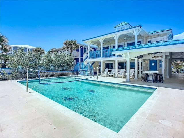 outdoor pool with stairs and a patio area