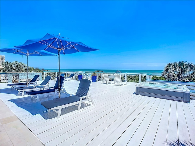 deck featuring a hot tub and a water view
