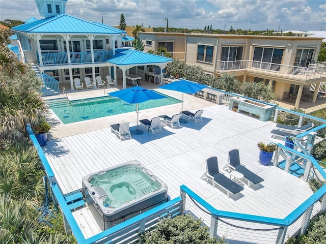 community pool with a deck, a hot tub, and outdoor dining space