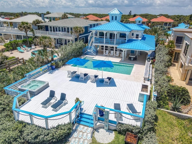 back of house with a balcony, a patio, and a pool with hot tub