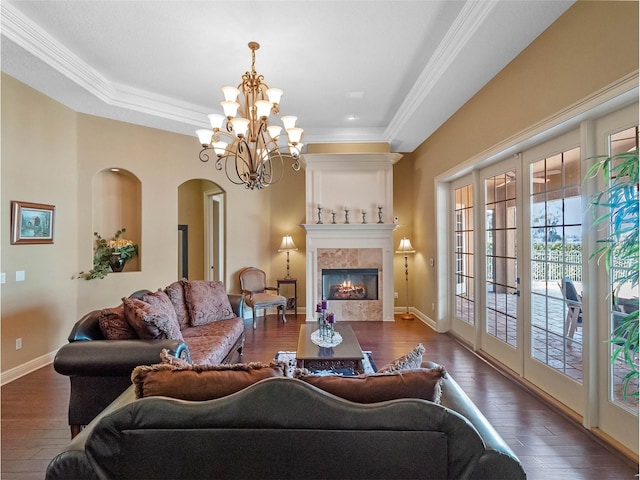 living area featuring crown molding, arched walkways, an inviting chandelier, and hardwood / wood-style floors
