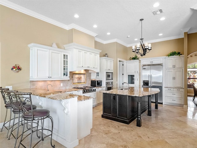 kitchen with crown molding, built in appliances, a breakfast bar area, a peninsula, and tasteful backsplash