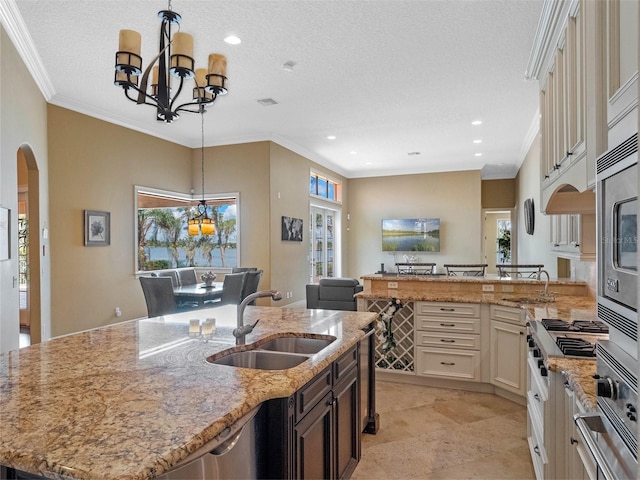 kitchen featuring a sink, arched walkways, an inviting chandelier, and a healthy amount of sunlight