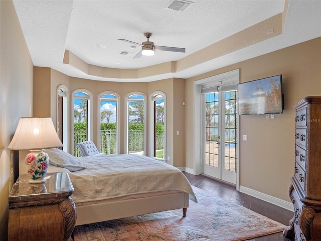 bedroom featuring visible vents, baseboards, access to outside, a raised ceiling, and hardwood / wood-style flooring