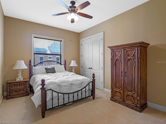 bedroom with light colored carpet, a ceiling fan, baseboards, and a closet