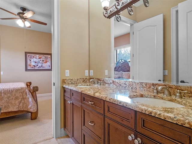 ensuite bathroom featuring connected bathroom, double vanity, ceiling fan, and a sink
