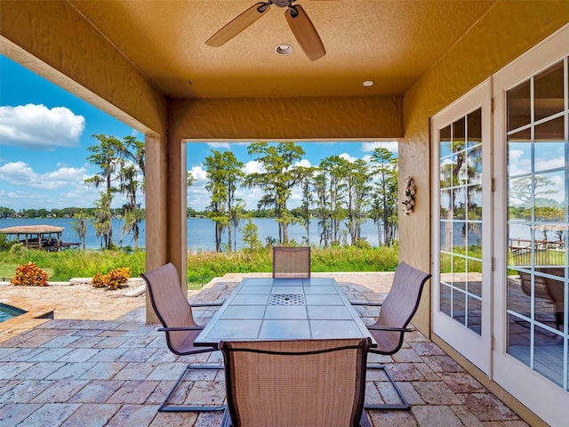 view of patio featuring a water view, ceiling fan, and outdoor dining area