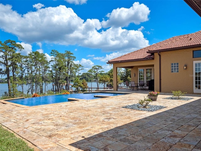 outdoor pool with a water view and a patio area