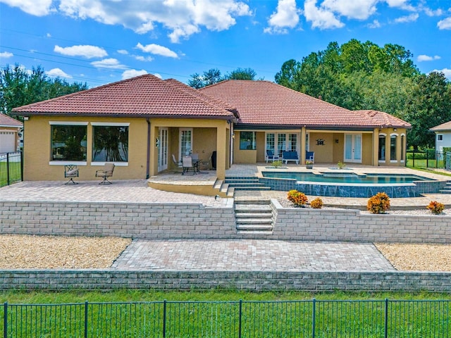 rear view of property with a tiled roof, french doors, a patio area, a fenced backyard, and stucco siding