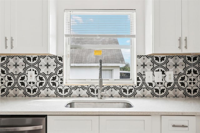 kitchen with stainless steel dishwasher, sink, white cabinets, and tasteful backsplash