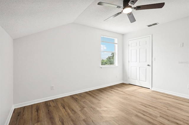 empty room with lofted ceiling, hardwood / wood-style floors, ceiling fan, and a textured ceiling