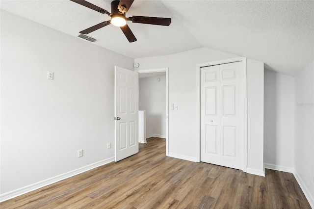 unfurnished bedroom featuring lofted ceiling, ceiling fan, hardwood / wood-style flooring, and a textured ceiling