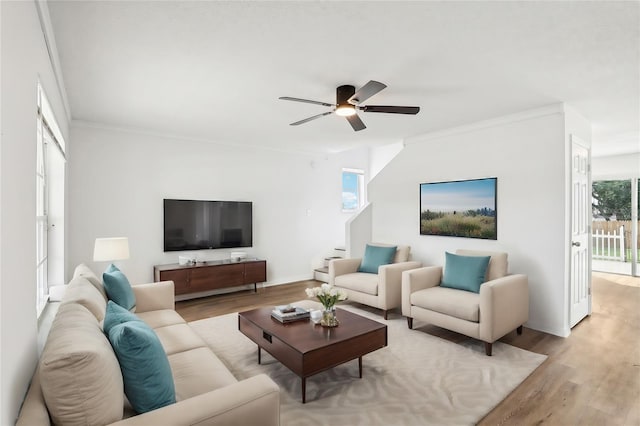 living area with stairs, ornamental molding, light wood finished floors, and ceiling fan