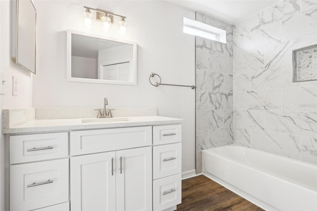 bathroom with wood-type flooring, tiled shower / bath, and vanity