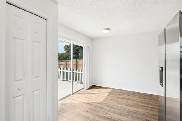 spare room with a textured ceiling and light wood-type flooring