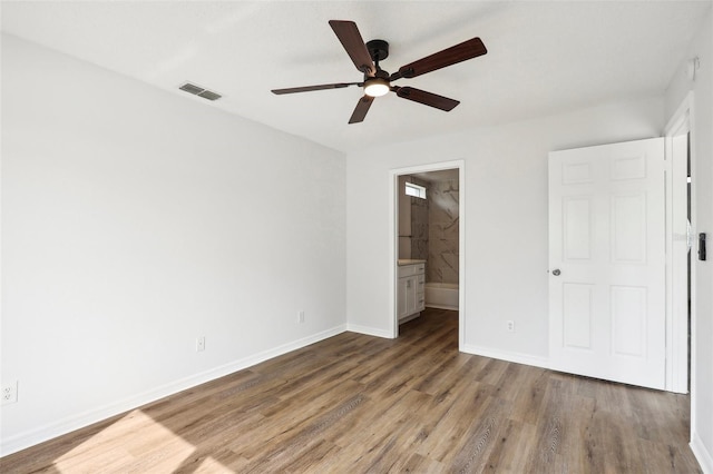 unfurnished bedroom with hardwood / wood-style floors, ceiling fan, and ensuite bath