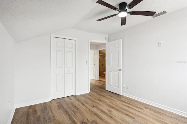 unfurnished bedroom featuring a closet, vaulted ceiling, ceiling fan, and light hardwood / wood-style floors