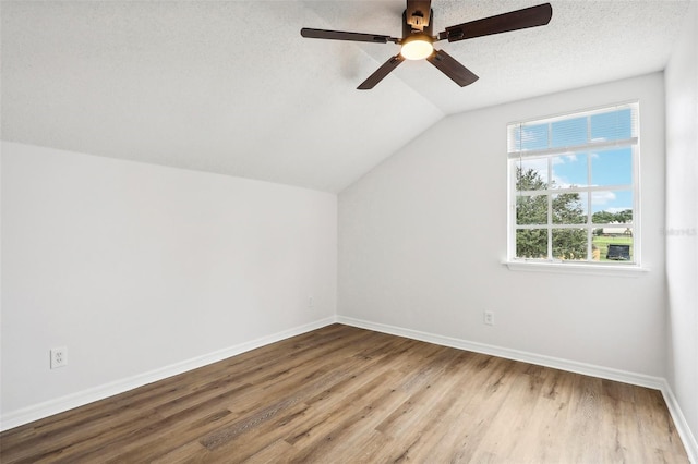 additional living space with a textured ceiling, ceiling fan, hardwood / wood-style floors, and vaulted ceiling