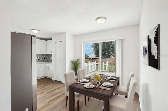 dining area with a textured ceiling and light wood-type flooring