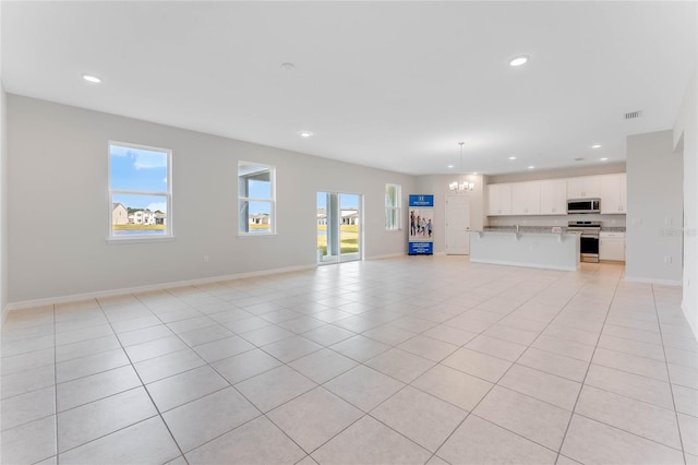 unfurnished living room featuring an inviting chandelier, plenty of natural light, and light tile patterned floors