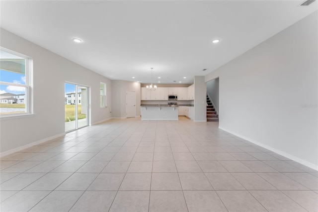 unfurnished living room featuring an inviting chandelier and light tile patterned floors