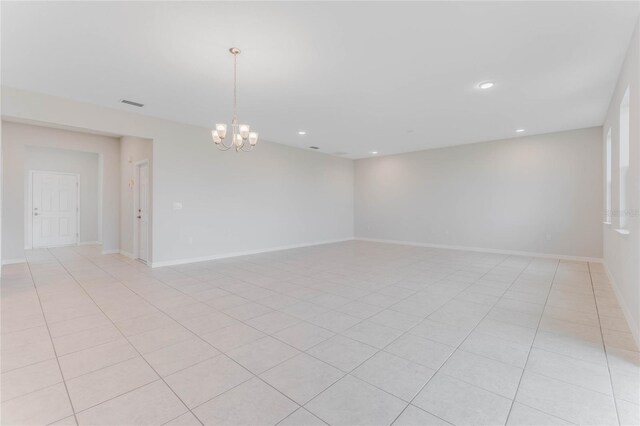 tiled empty room featuring an inviting chandelier