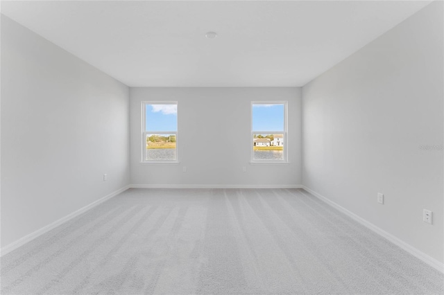 unfurnished room featuring light colored carpet and baseboards