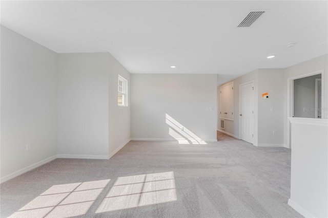 spare room featuring light carpet, visible vents, recessed lighting, and baseboards