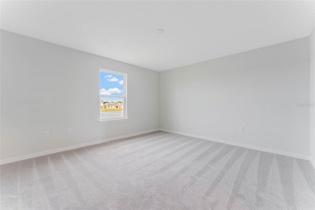 unfurnished room with baseboards and light colored carpet