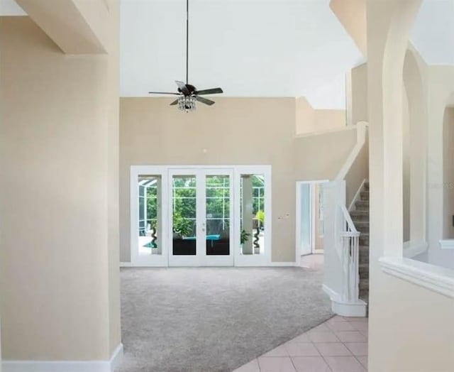 carpeted living room featuring a towering ceiling and ceiling fan