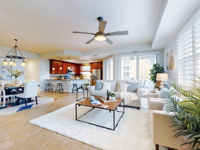 tiled living room featuring ceiling fan with notable chandelier