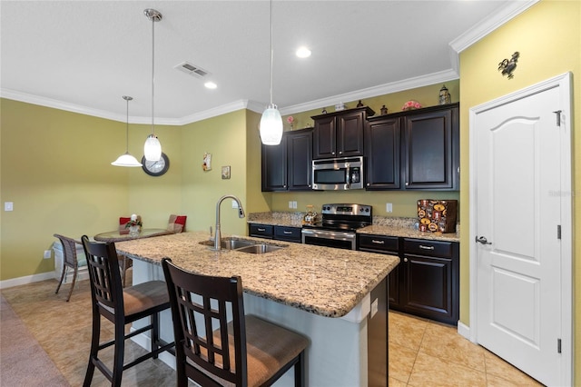 kitchen with pendant lighting, a kitchen bar, stainless steel appliances, sink, and a center island with sink