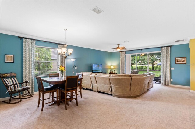 dining space featuring ceiling fan with notable chandelier, light colored carpet, and ornamental molding